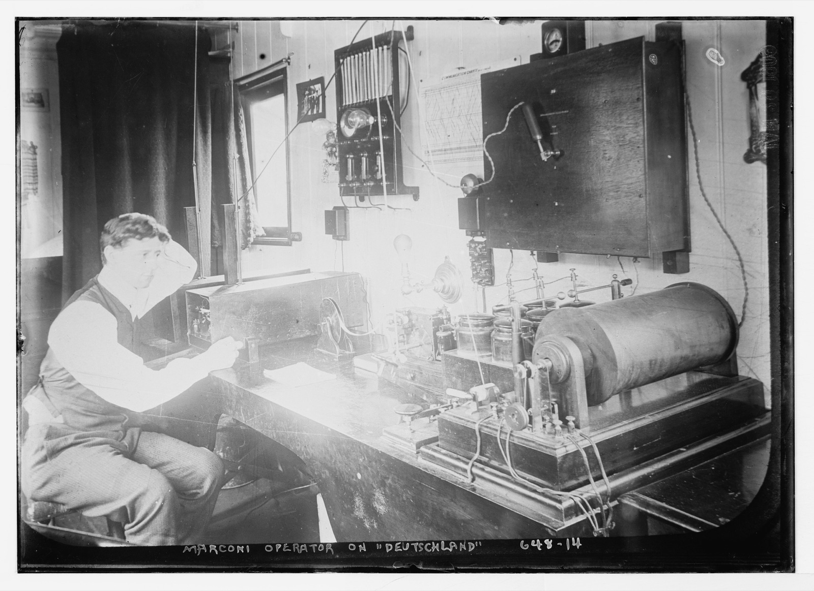 A Marconi wireless telegraph operator seated at his instruments aboard the steamship Deutschland, in an early-1900s black-and-white photograph.